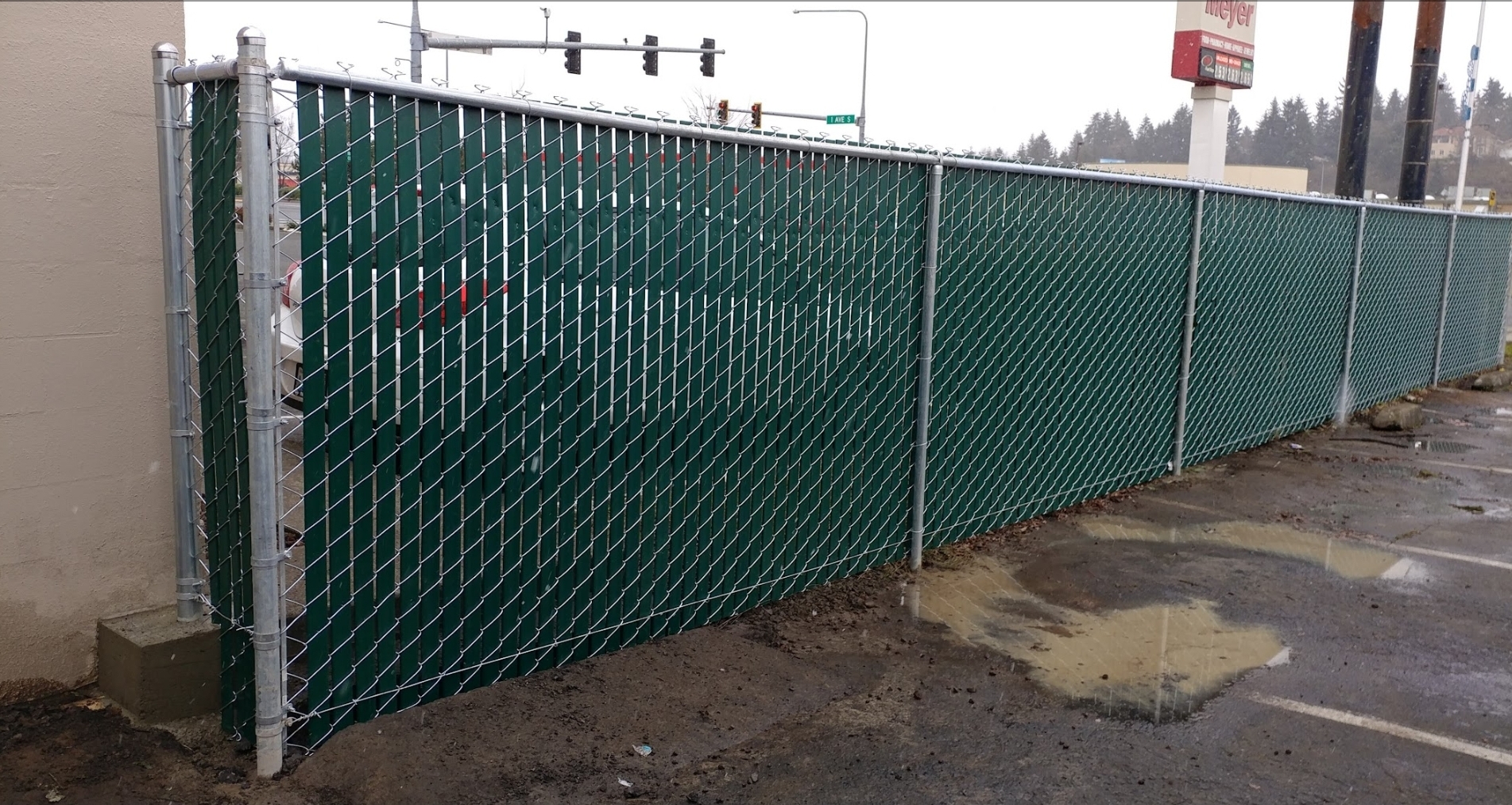 GALVANIZED CHAIN LINK FENCE WITH GREEN PRIVACY SLATS.