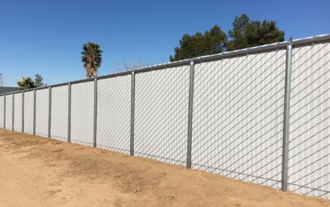 GALVANISED CHAIN LINK FENCE WITH WHITE PRIVACY SLATS.