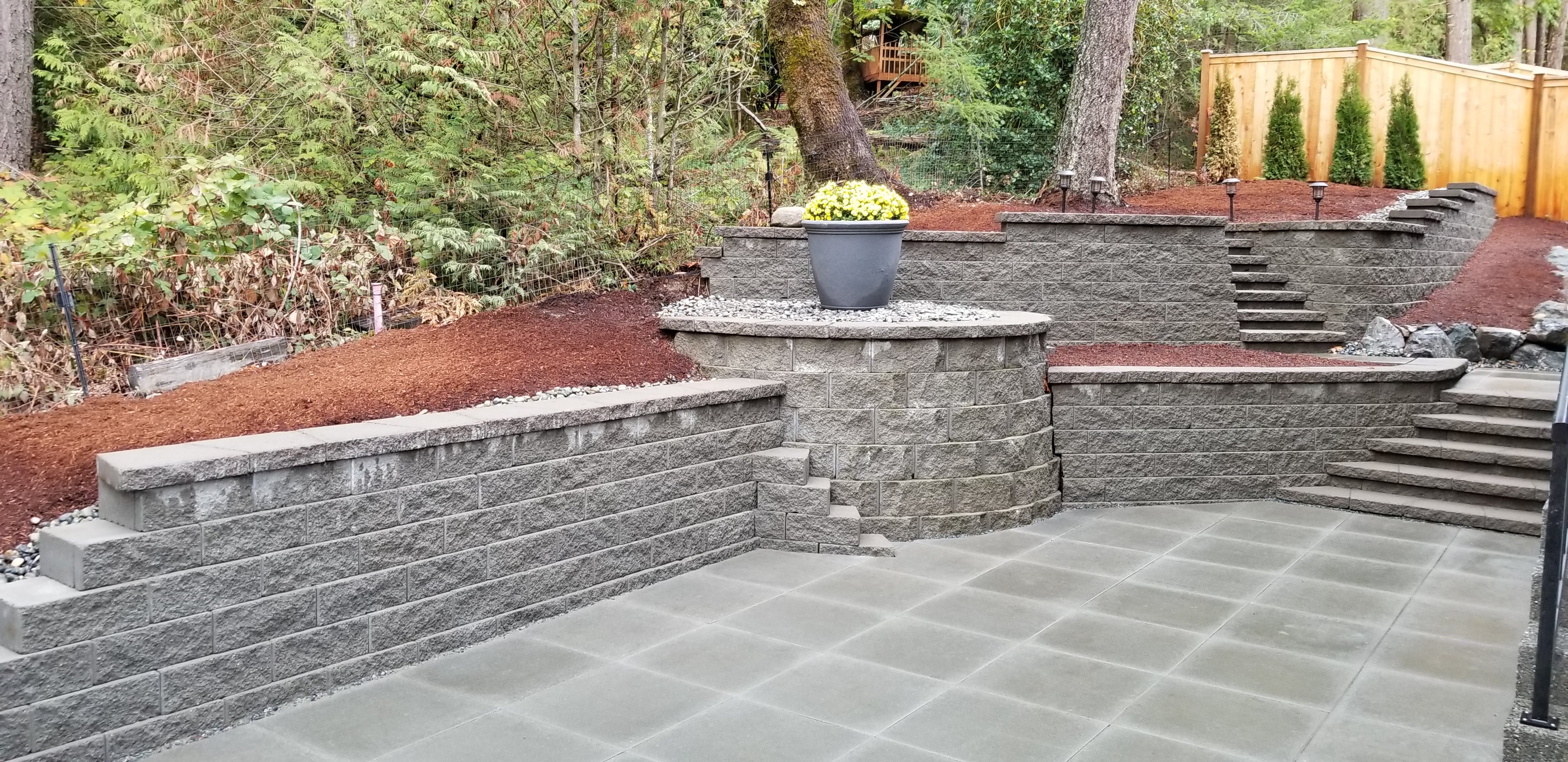 PATIO WITH VANCOUVER BAY SLABS GRAY AND RETAINING WALLS WITH MANORSTONE BLOCKS GRAY.